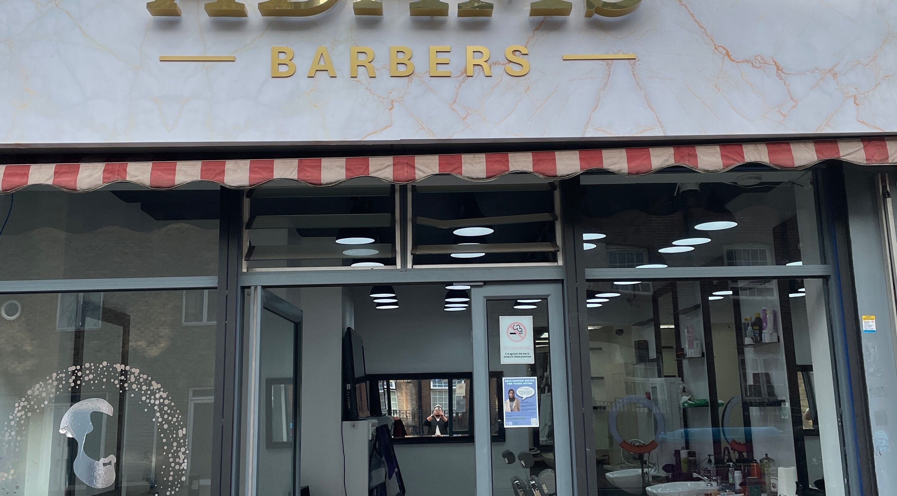 Front view of Adams Barber shop in London, England, GB with stylish signage and inviting interior.