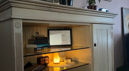 Serene shelf at H.E.R - Heal. Embody. Rise, Cape Town, with a glowing salt lamp and wellness books.