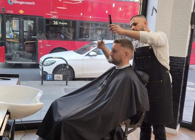 Stylist at MOSS Salon in London, England, GB gives customer a haircut near a city view window.