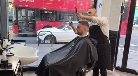 Stylist at MOSS Salon in London, England, GB gives customer a haircut near a city view window.