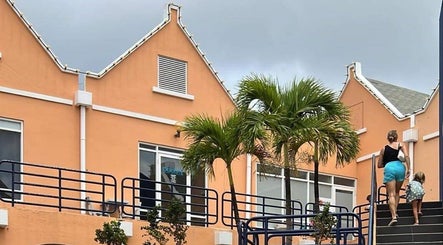 Exquisite Curaçao venue in Willemstad, Curaçao, CW, with vibrant orange building and lush palm trees.