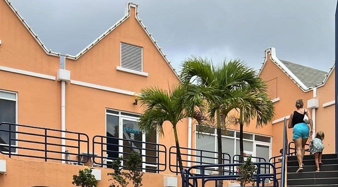 Exquisite Curaçao venue in Willemstad, Curaçao, CW, with vibrant orange building and lush palm trees.