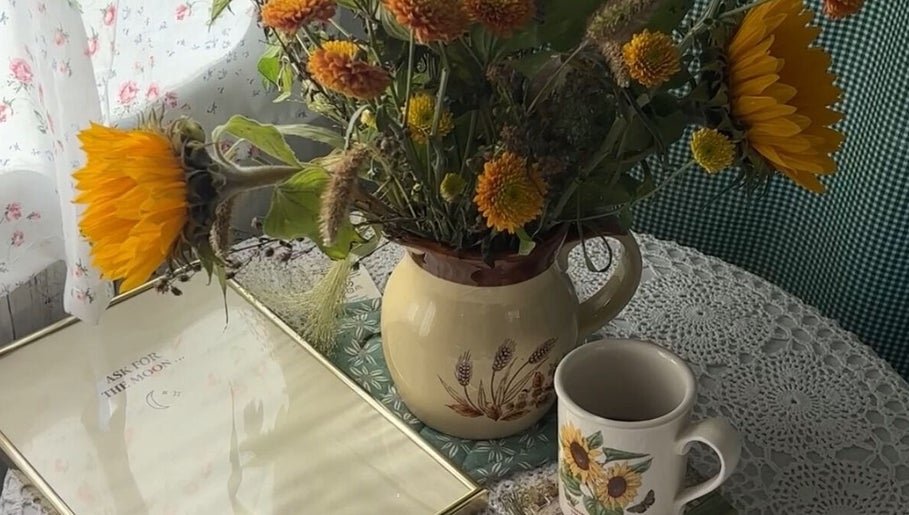 Charming floral display at Lash Ark, Worcester Park, England. Sunflowers in a rustic jug on a lace tablecloth.