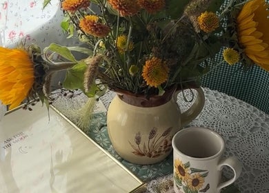 Charming floral display at Lash Ark, Worcester Park, England. Sunflowers in a rustic jug on a lace tablecloth.