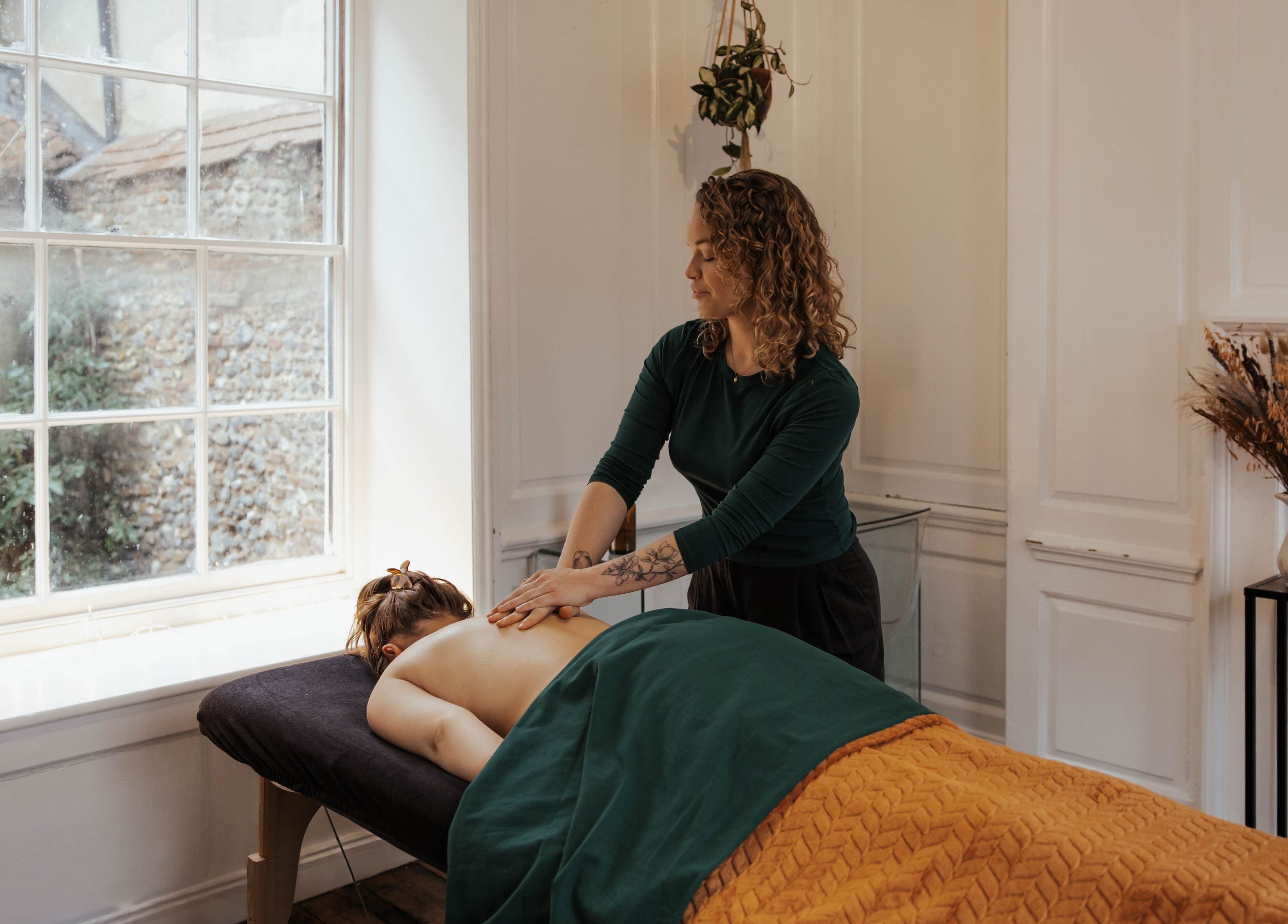 A massage therapist at The Elsewhere in Norwich, England, GB providing relaxing treatment in a calm room.