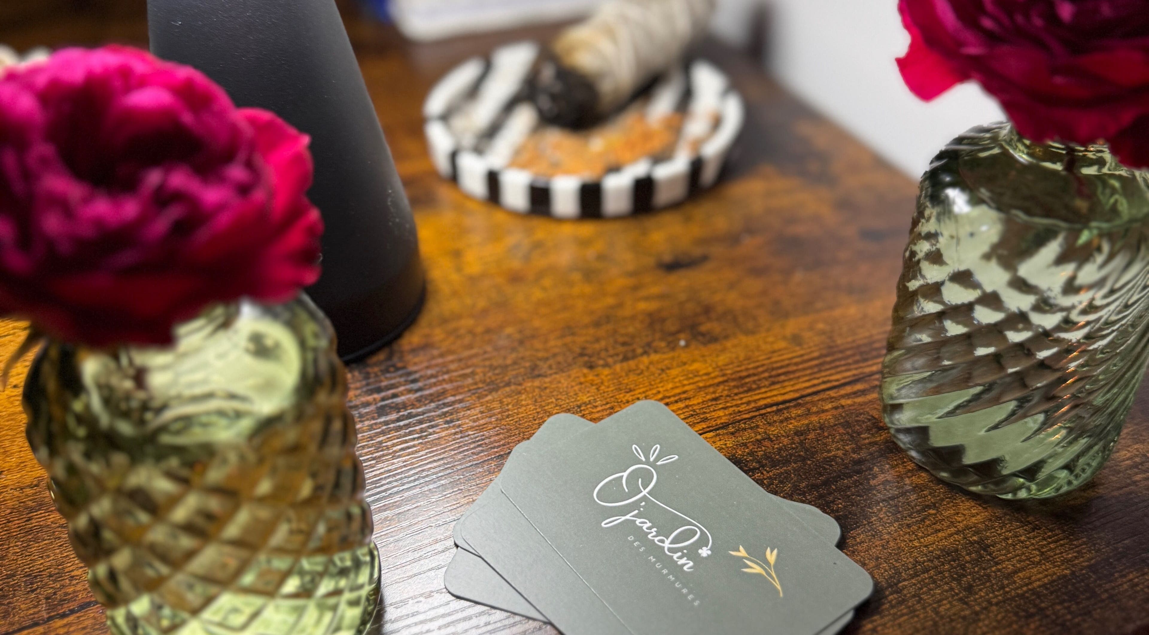 Cartes Ö Jardin Des Murmures Lavaur Occitanie sur une table avec fleurs décoratives.