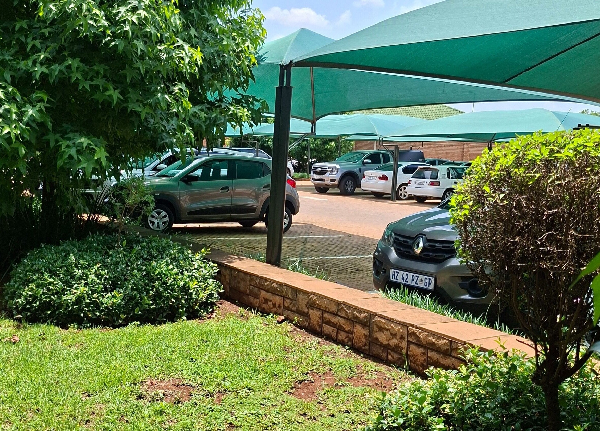 Greenery and parked cars outside Enchanted Nails by Tania, Pretoria, Gauteng, ZA.
