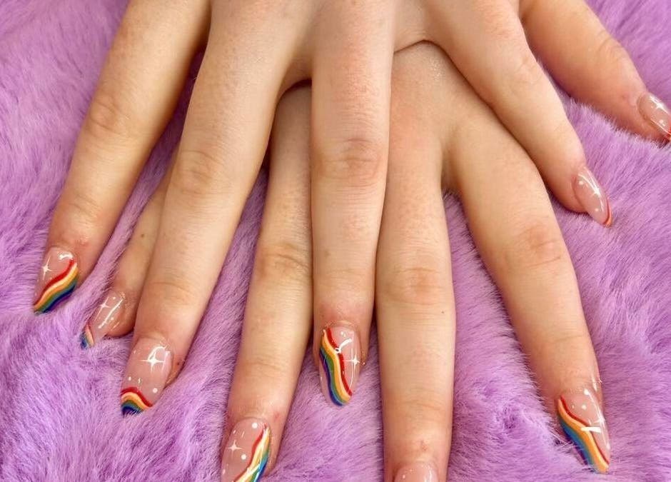 Stylish rainbow nail art at Sala Nails & Spa, Gosnells, Western Australia, AU. Vibrant colors on a plush purple background.