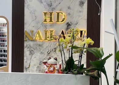 Lối vào HD NAIL ART, Warszawa, Województwo Mazowieckie, PL với bảng hiệu vàng sáng.
