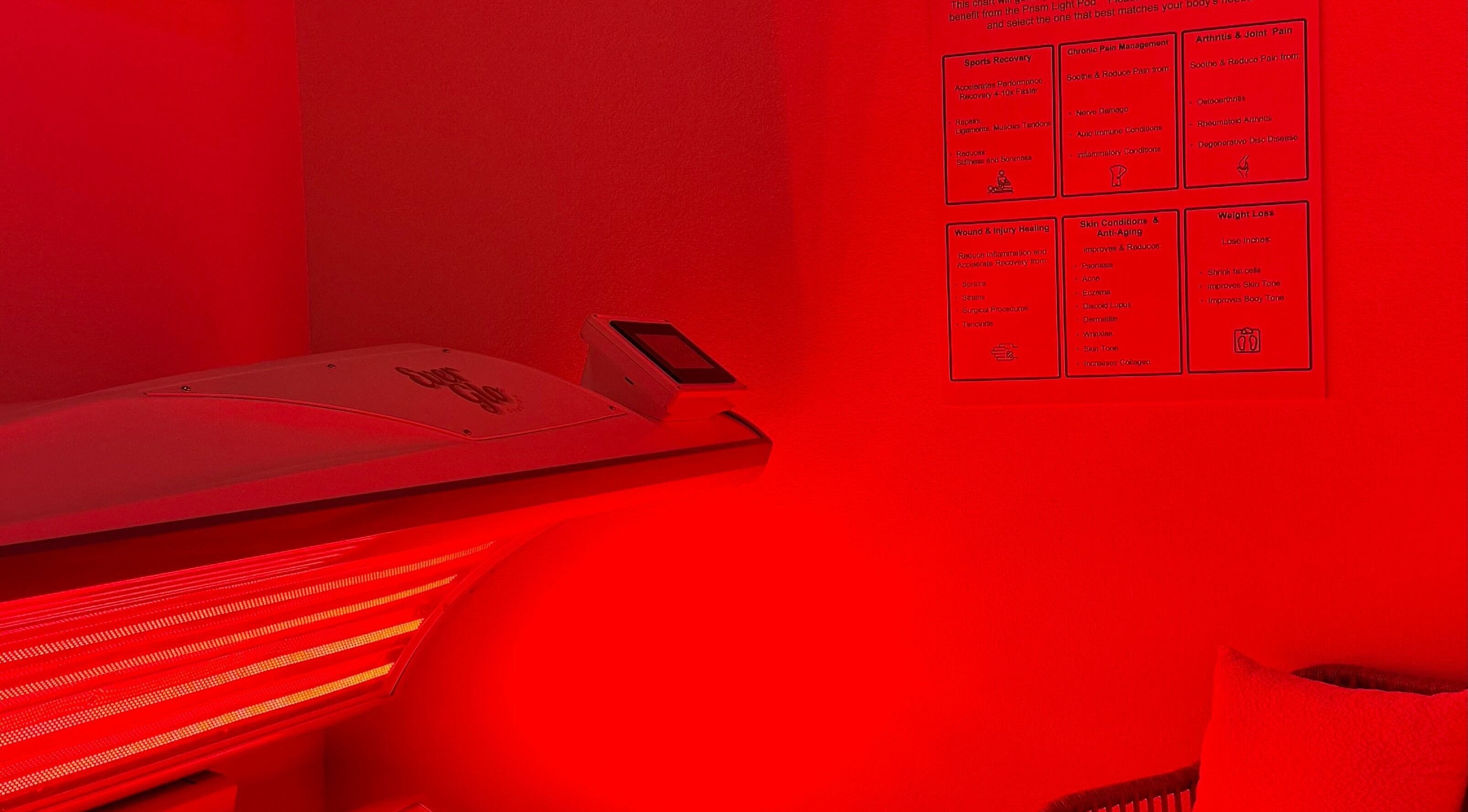 Red light therapy room in EverGlo Studios, Henderson, Nevada, US, showcasing equipment and benefits chart.