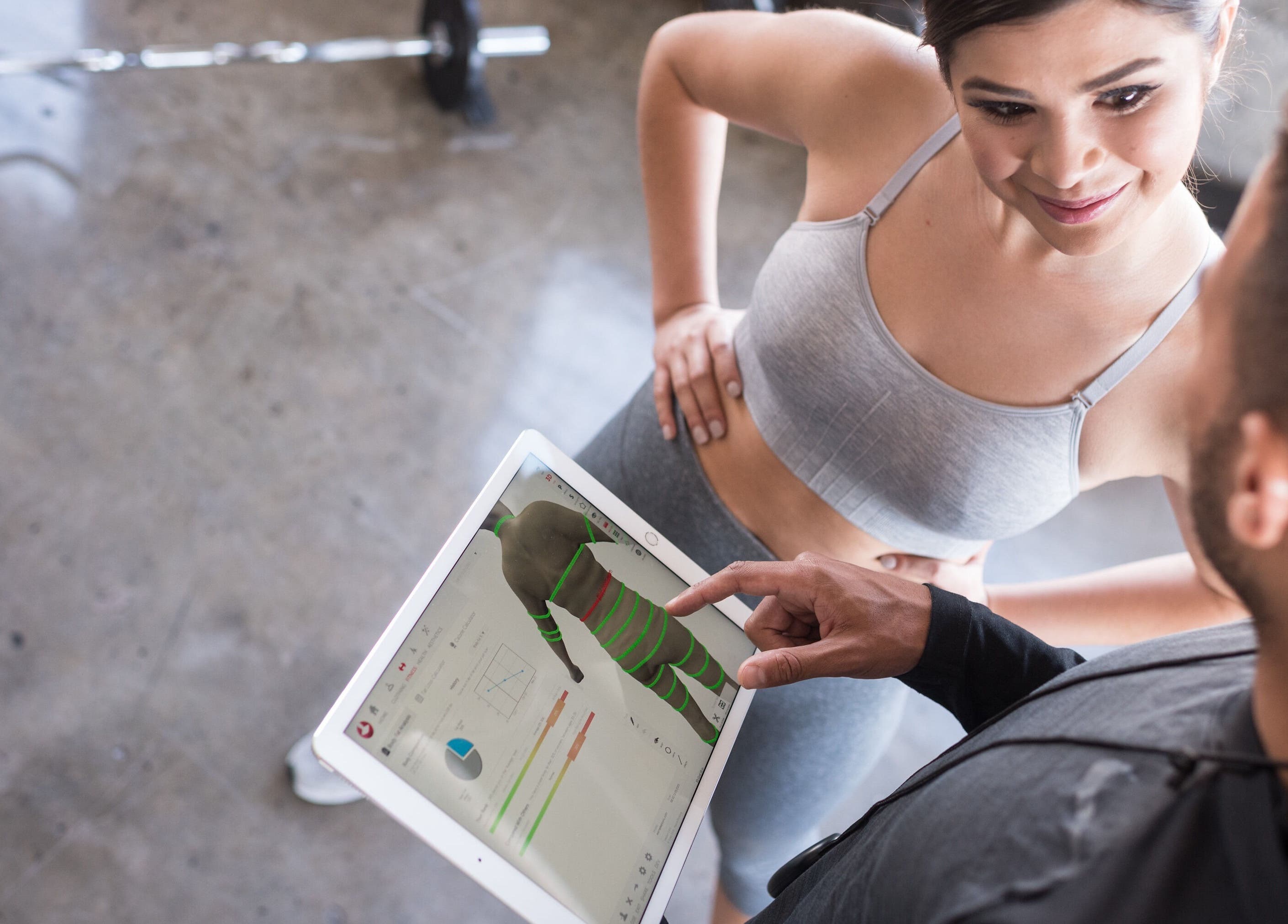 Personal trainer showing fitness data to client at EverGlo Studios, Henderson, Nevada, US.