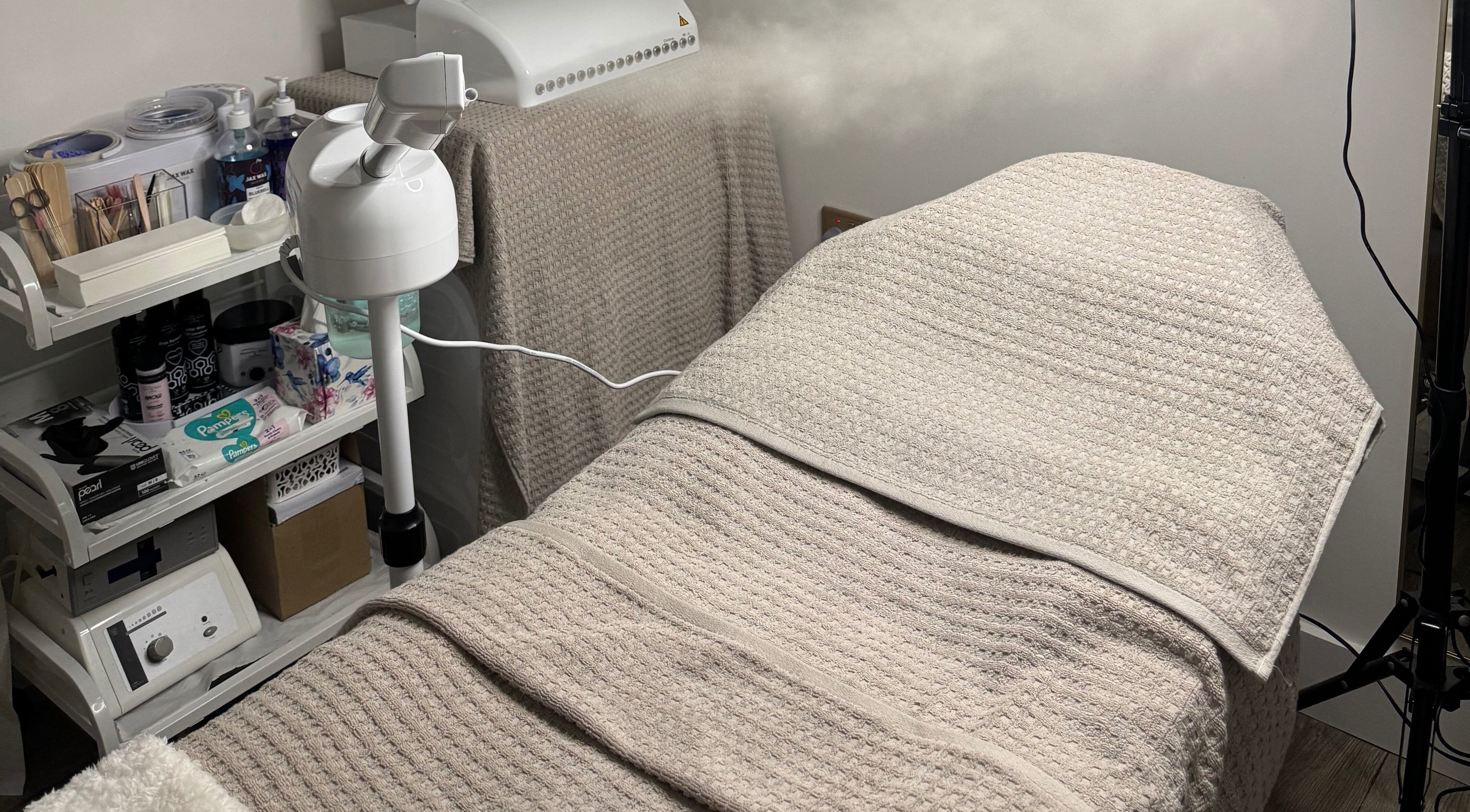 Treatment room at SkinFit, London, England, GB, featuring a cozy towel-covered bed and essential skincare tools.