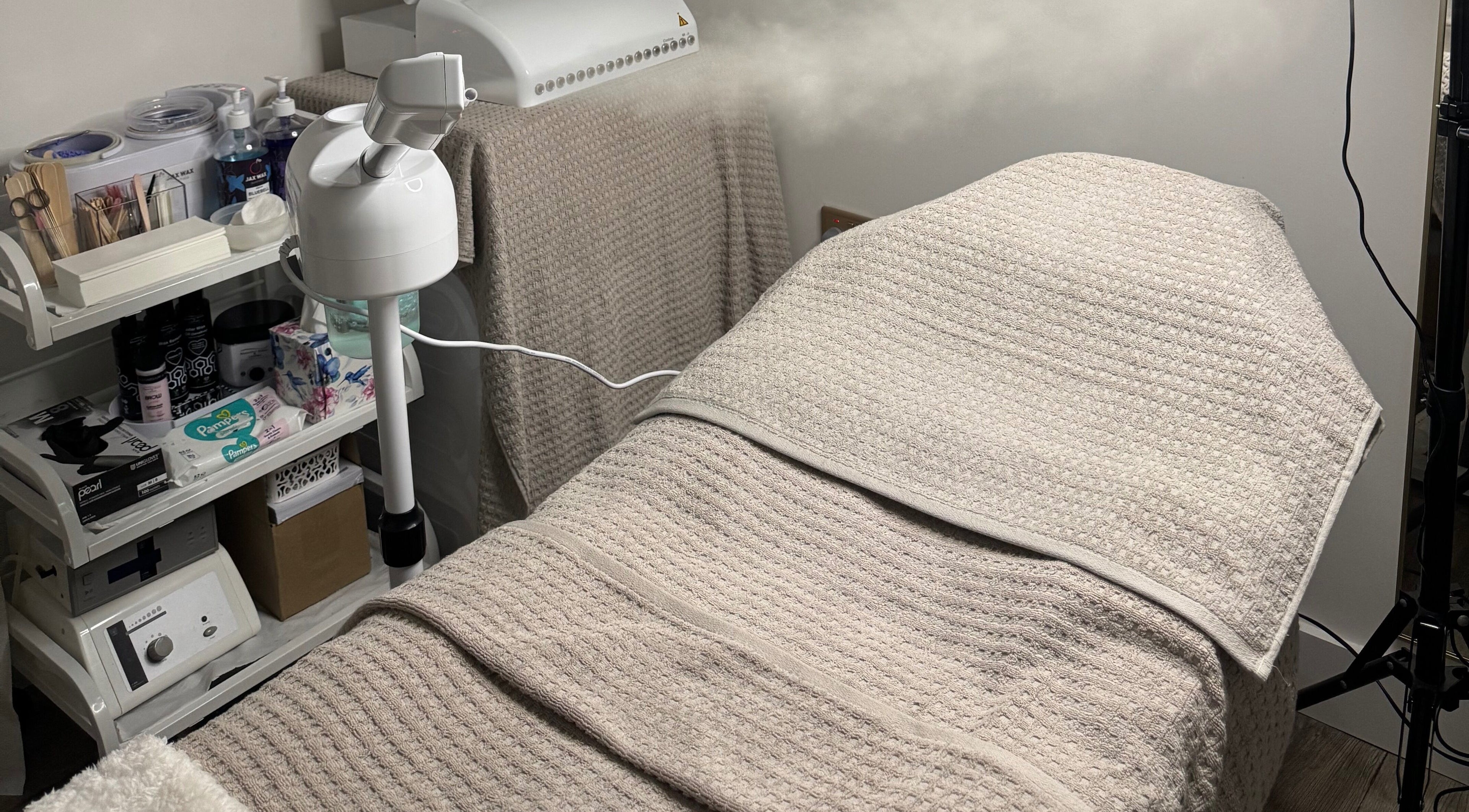 Treatment room at SkinFit, London, England, GB, featuring a cozy towel-covered bed and essential skincare tools.