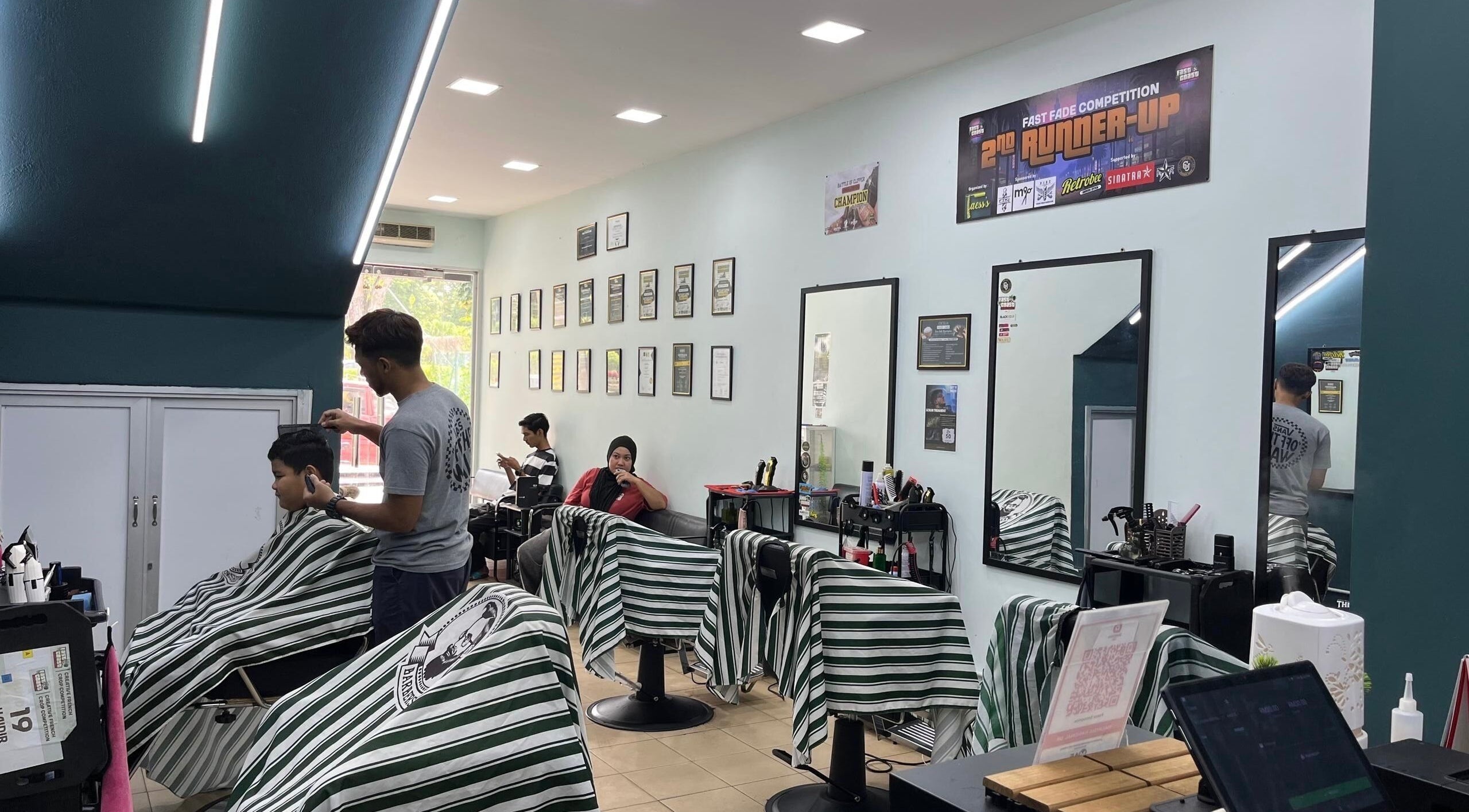 Faess Barbershop in Kuantan, Pahang, MY featuring a modern interior with clients receiving haircuts.