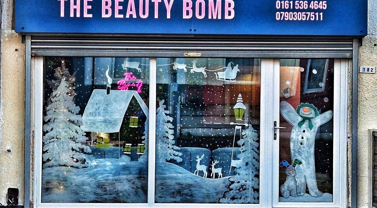 Festive window art at DMD Aesthetics in Eccles, England, GB showcasing winter scenes.