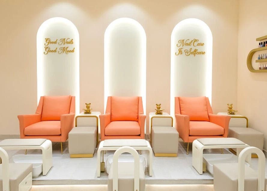 Modern nail care area at Flourish Beauty Lounge & Spa in Dubai, AE, featuring stylish coral and gold seating.