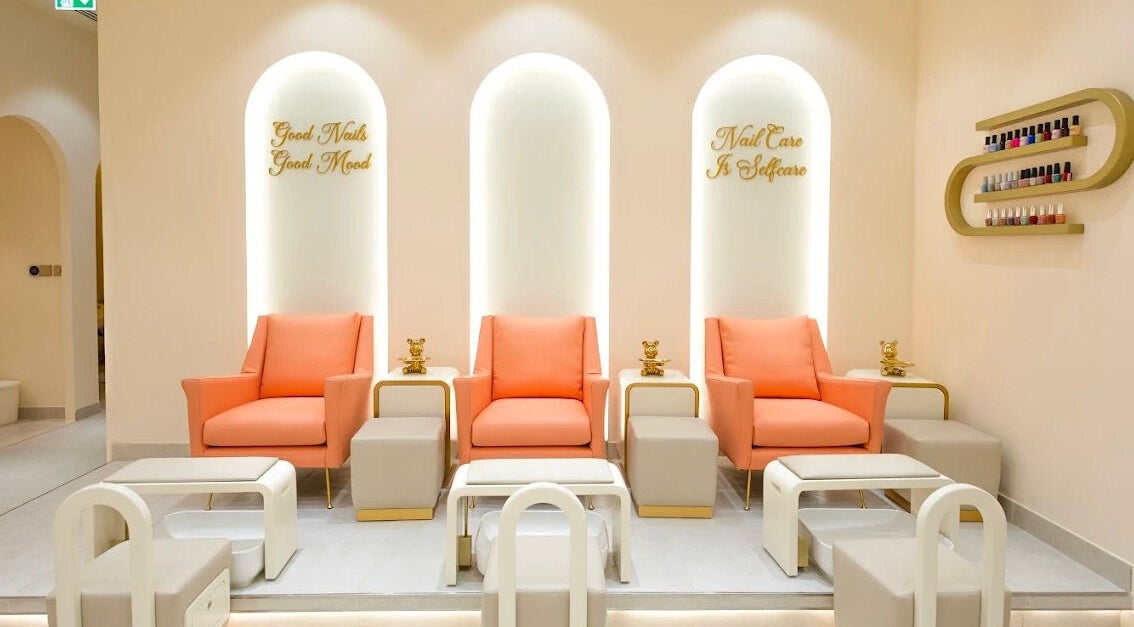 Modern nail care area at Flourish Beauty Lounge & Spa in Dubai, AE, featuring stylish coral and gold seating.