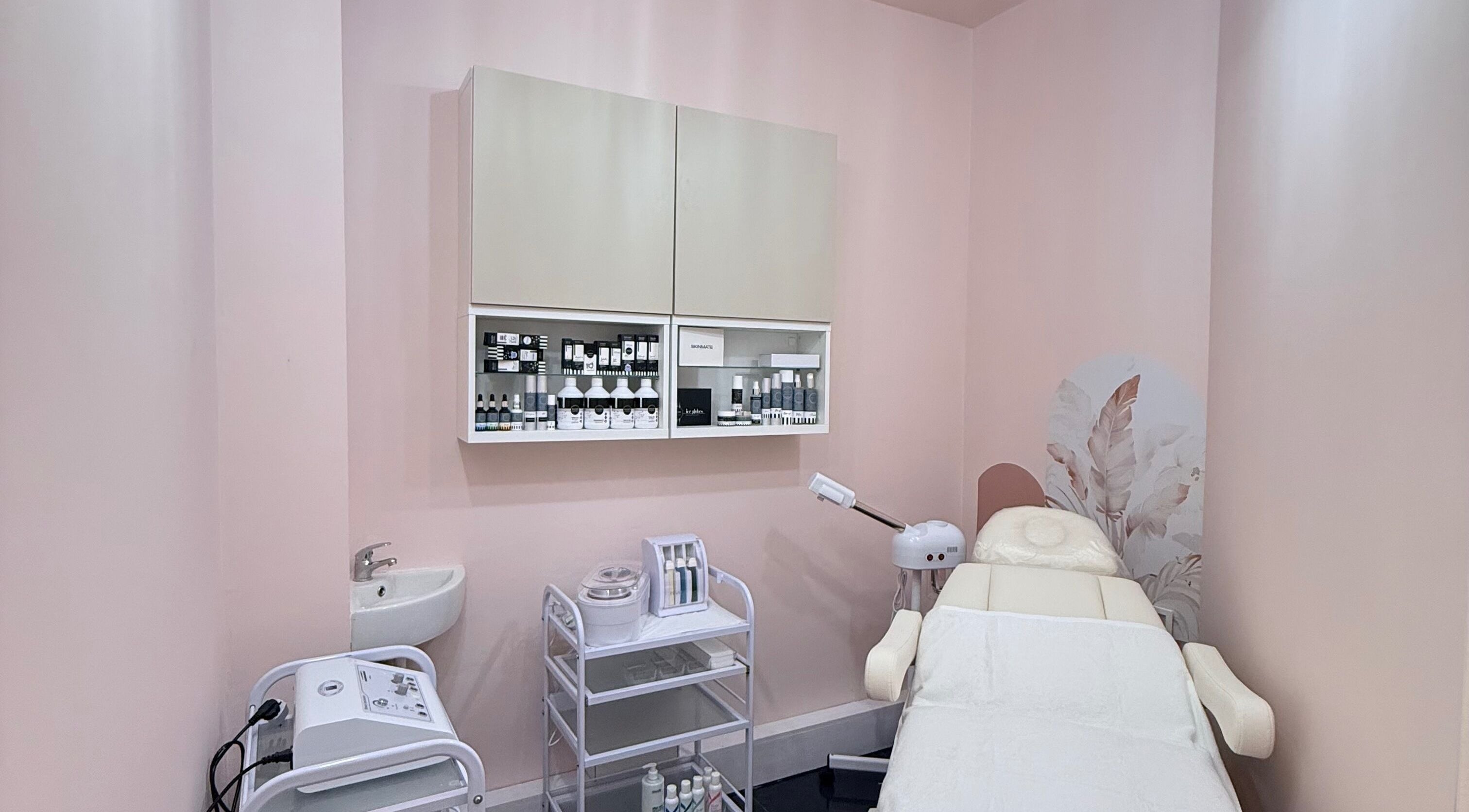 Treatment room at Elegance Beauty and Aesthetics, London, England, GB with pink decor and skincare products.