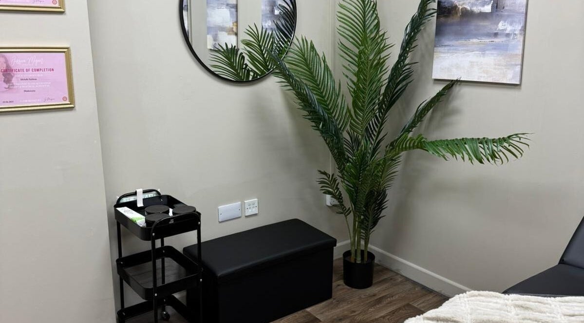 Peaceful corner at Pearls of Beauty, Hastings, England, GB with plant, mirror, and certificates.