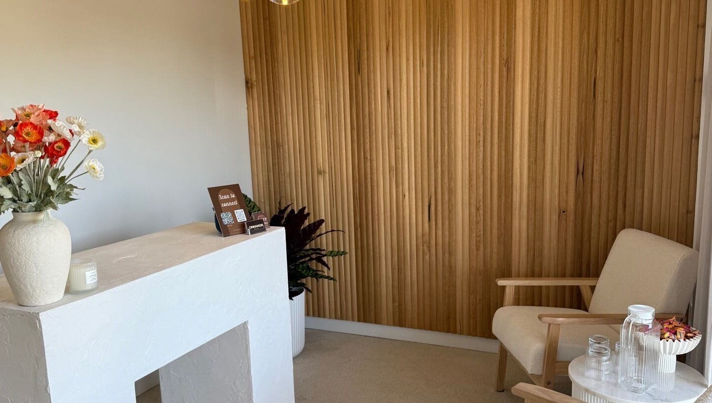 Cozy reception area at Tyde Beauty Studio in Southport, Queensland, AU with wooden decor and floral accents.