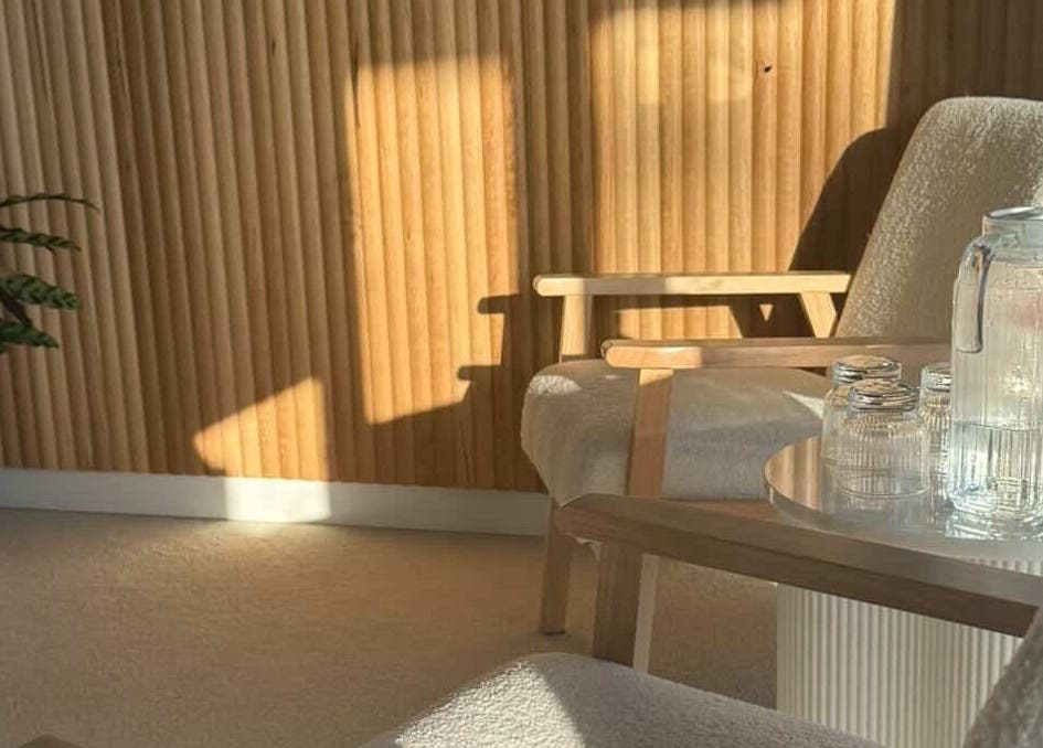 Cozy lounge area at Tyde Beauty Studio, Southport, Queensland, AU with wooden accents and sunlight.