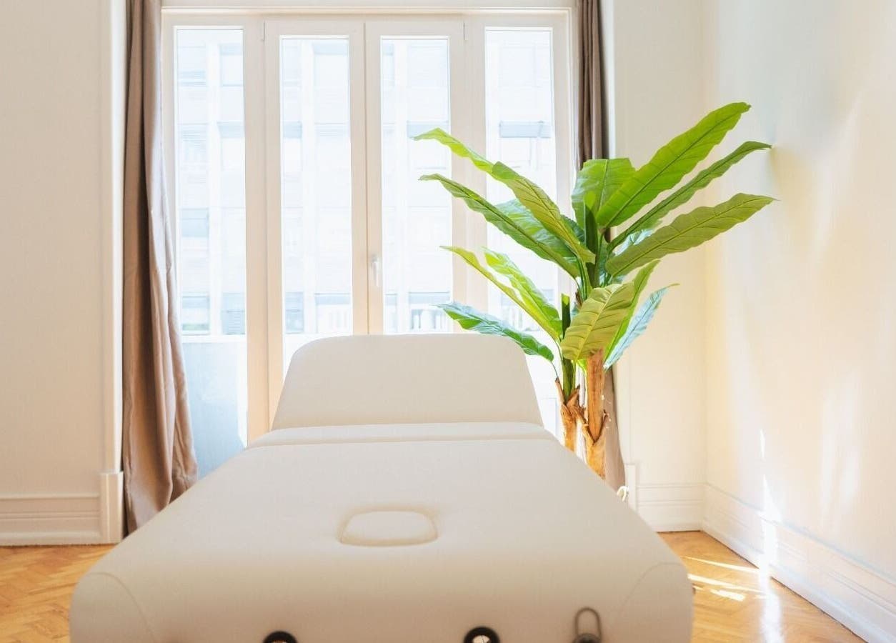 Sala de massagem iluminada no Wellzen by Diana, Lisboa, Lisboa, PT, com cama branca e planta decorativa.