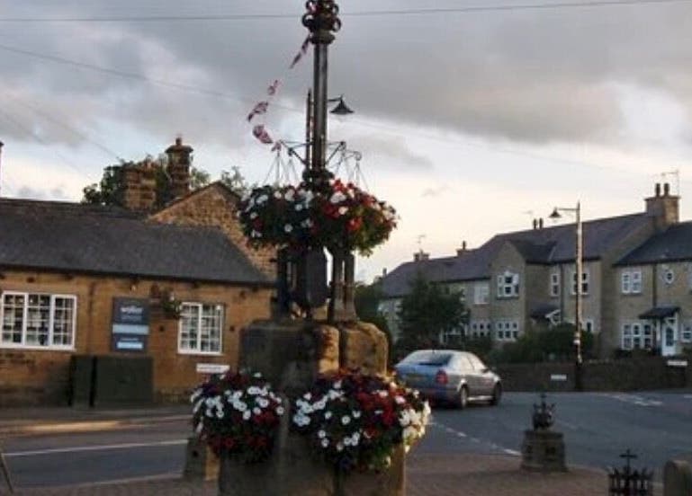 Charming street view near BuildbyBella in Otley, England with historic stone buildings and floral displays.