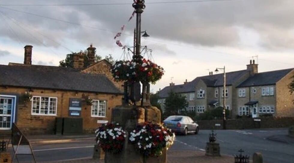 Charming street view near BuildbyBella in Otley, England with historic stone buildings and floral displays.