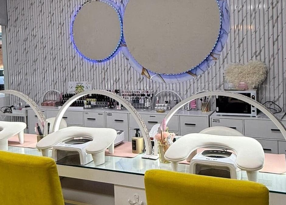 Interior moderno de Estética la favorita, Alcalá De Henares, con estaciones de manicura blancas y espejos circulares.