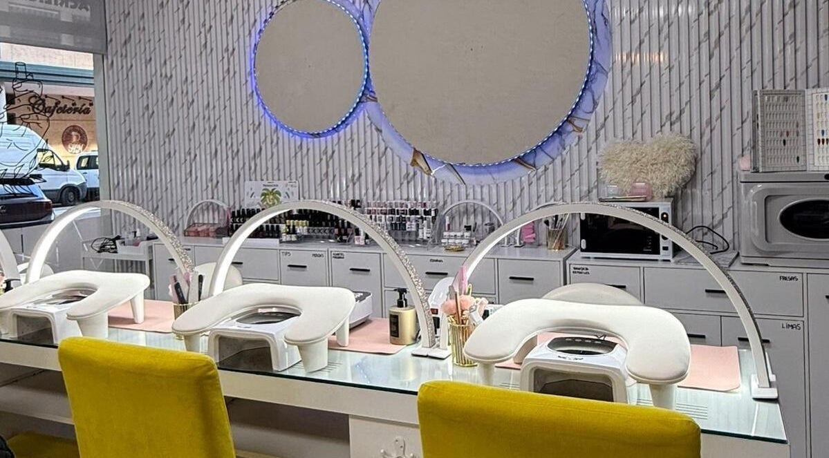 Interior moderno de Estética la favorita, Alcalá De Henares, con estaciones de manicura blancas y espejos circulares.