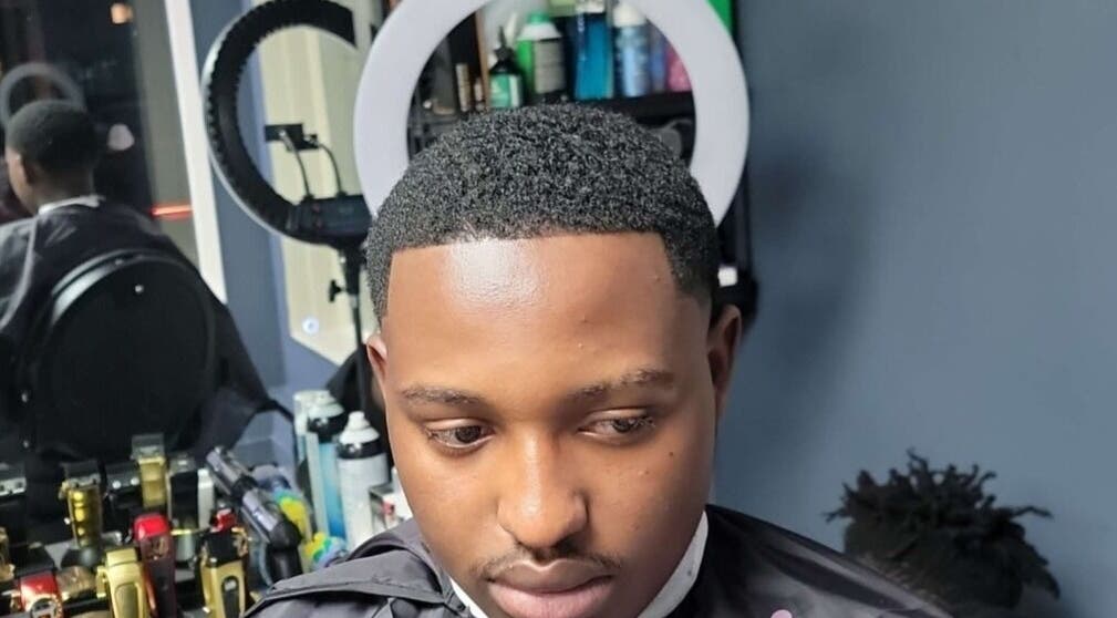 Man receives haircut at Bobo Classique, Joliette, Québec, CA with a stylish ring light setup.