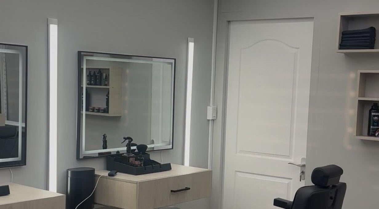 Interieur van Dreamchasers Barbershop in Willemstad, Curaçao, met moderne spiegels en kappersstoel.