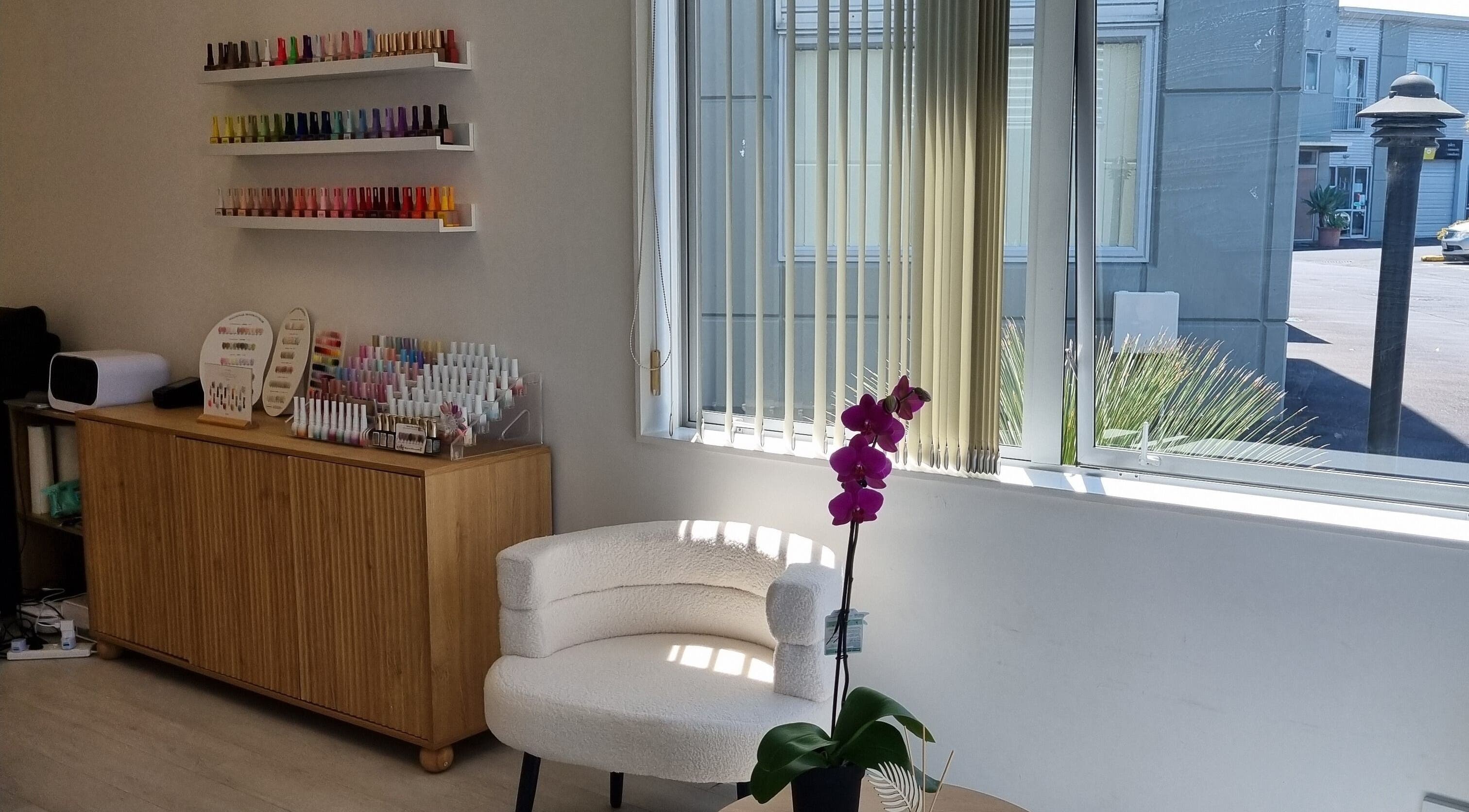 Elegant interior of Juju Beauty Studio in Auckland, NZ with nail polish display and cozy seating.