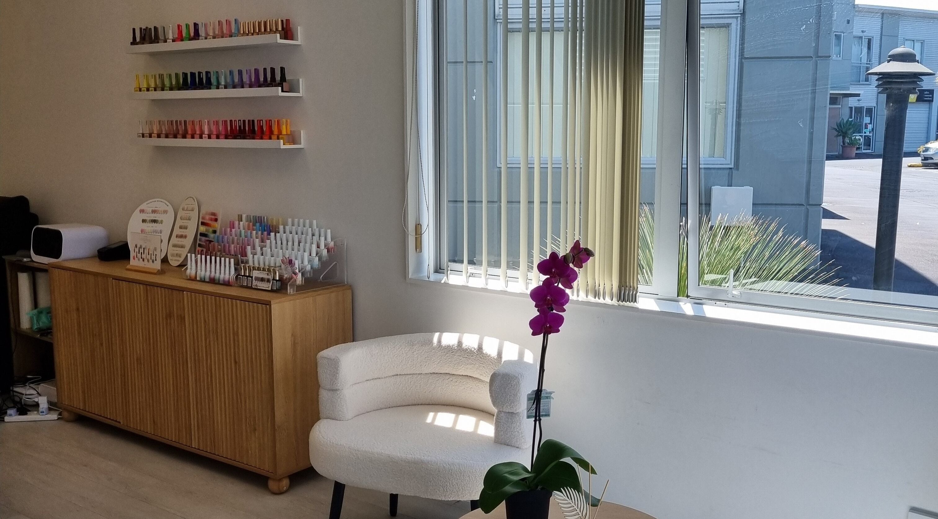 JuJu beauty studio in Auckland, NZ featuring a vibrant nail polish display and cozy seating by the window.