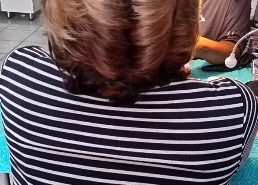 Back of a woman receiving a manicure at Sheckies Hair and Beauty Salon, Cape Town, Western Cape, ZA.