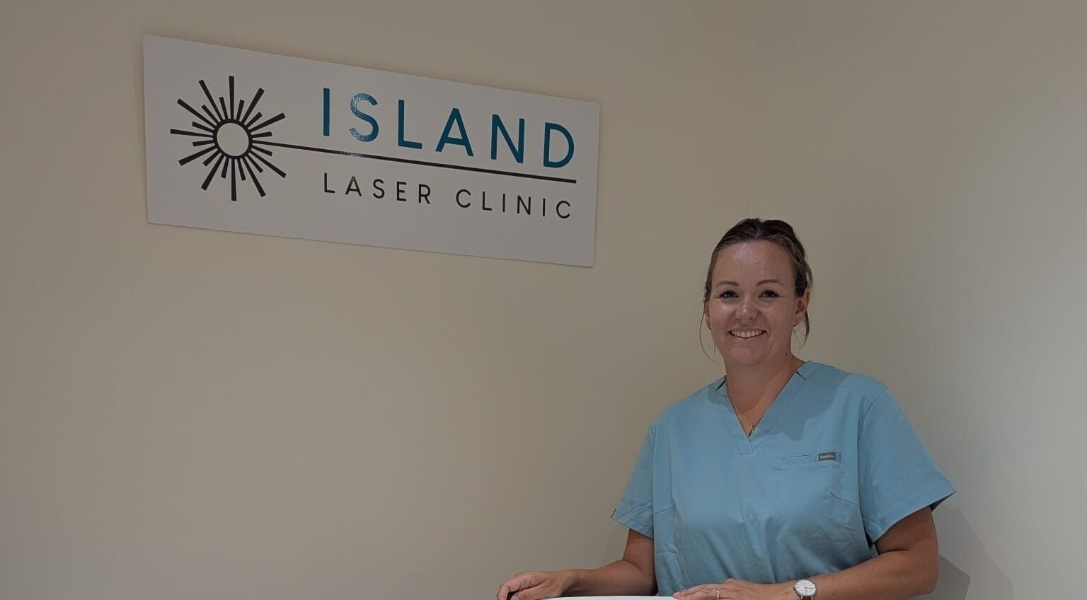 A smiling staff member at Island Laser Clinic, Hayling Island, England, GB, standing proudly by the clinic sign.