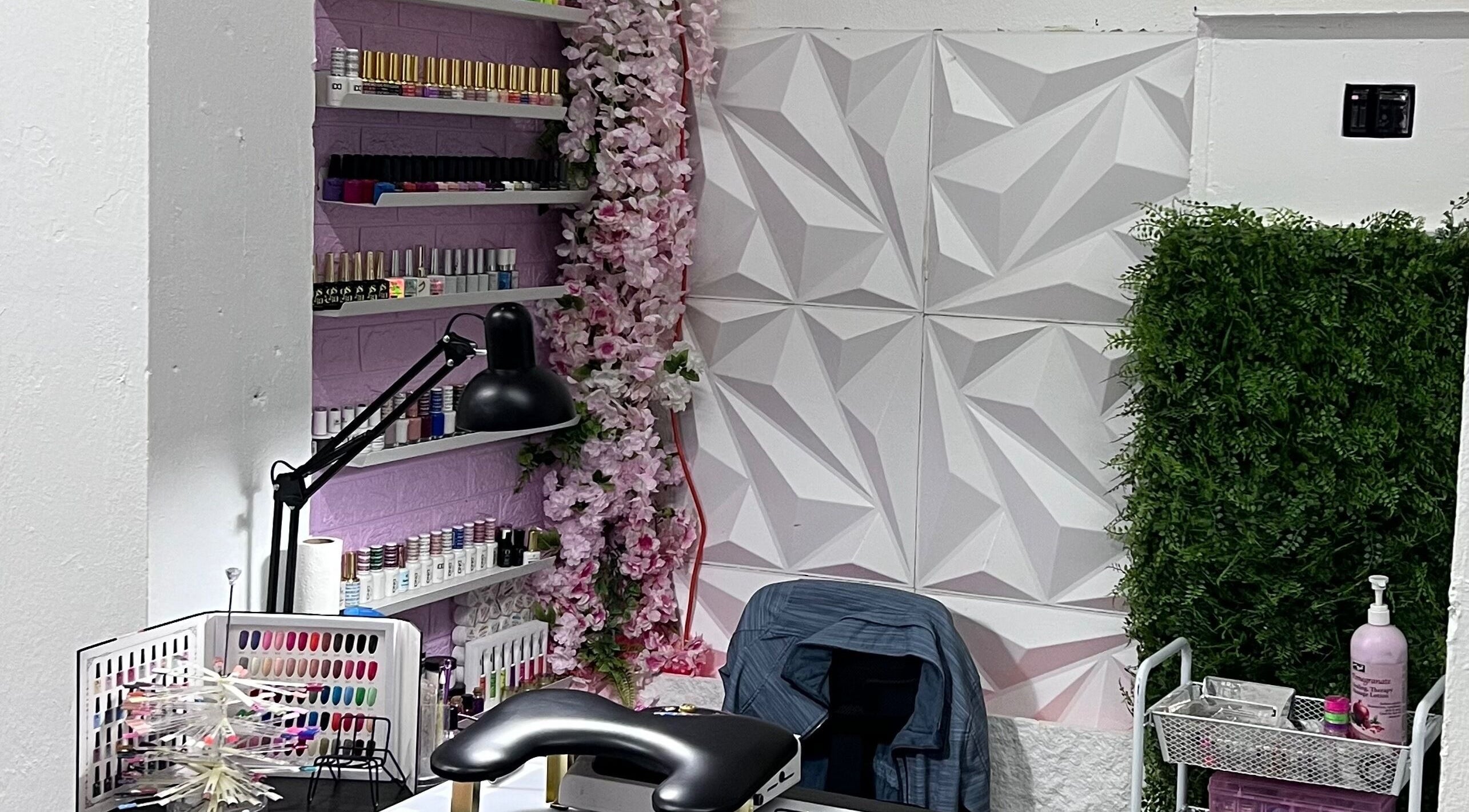 Estante de esmaltes en IsaNailSpa, Bayamón, Bayamón, PR, con decoración en paredes y lámpara moderna.
