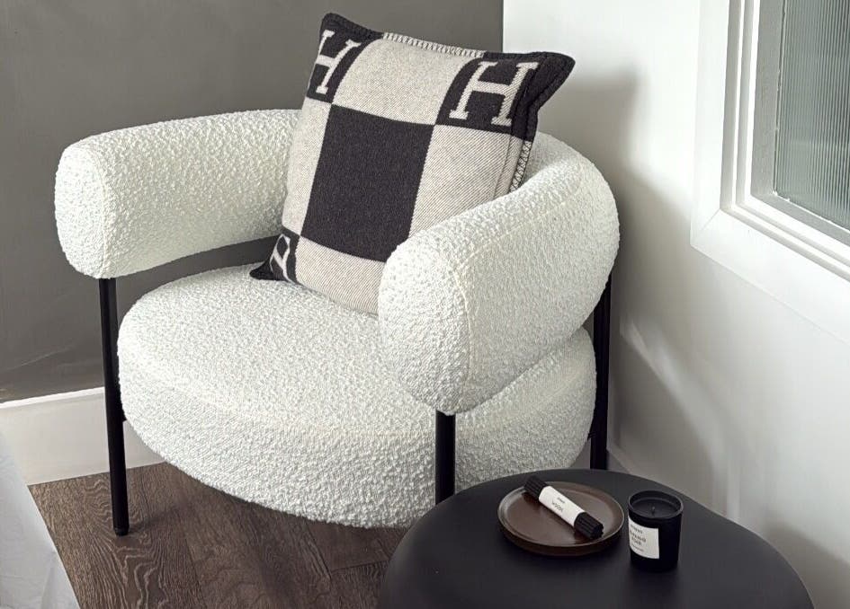 Elegant chair with designer pillow beside a table at Haus of Sar, London, England, GB.