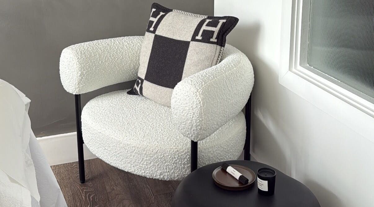 Elegant chair with designer pillow beside a table at Haus of Sar, London, England, GB.