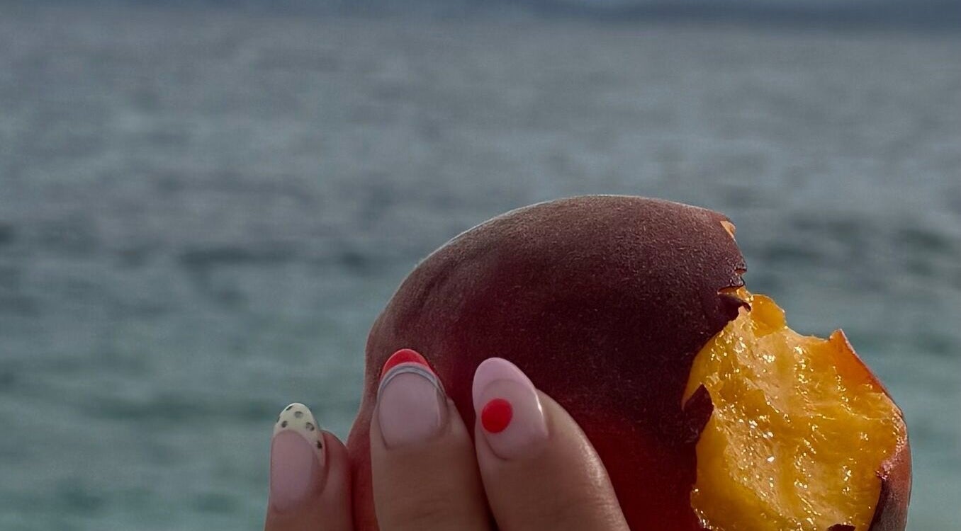 Stylish nail art at The Nail Shop, Mountsorrel, England, GB by the sea, holding a juicy peach.