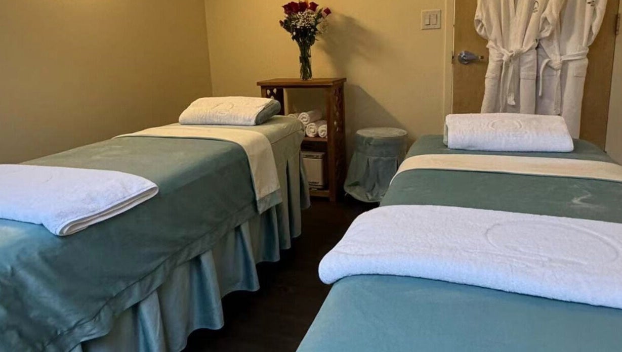 Two massage tables at Relax Day Spa, New York, New York, US, adorned with fresh linens and roses.
