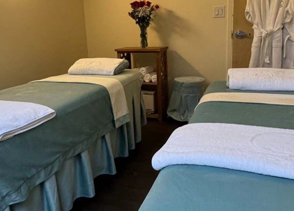 Two massage tables at Relax Day Spa, New York, New York, US, adorned with fresh linens and roses.