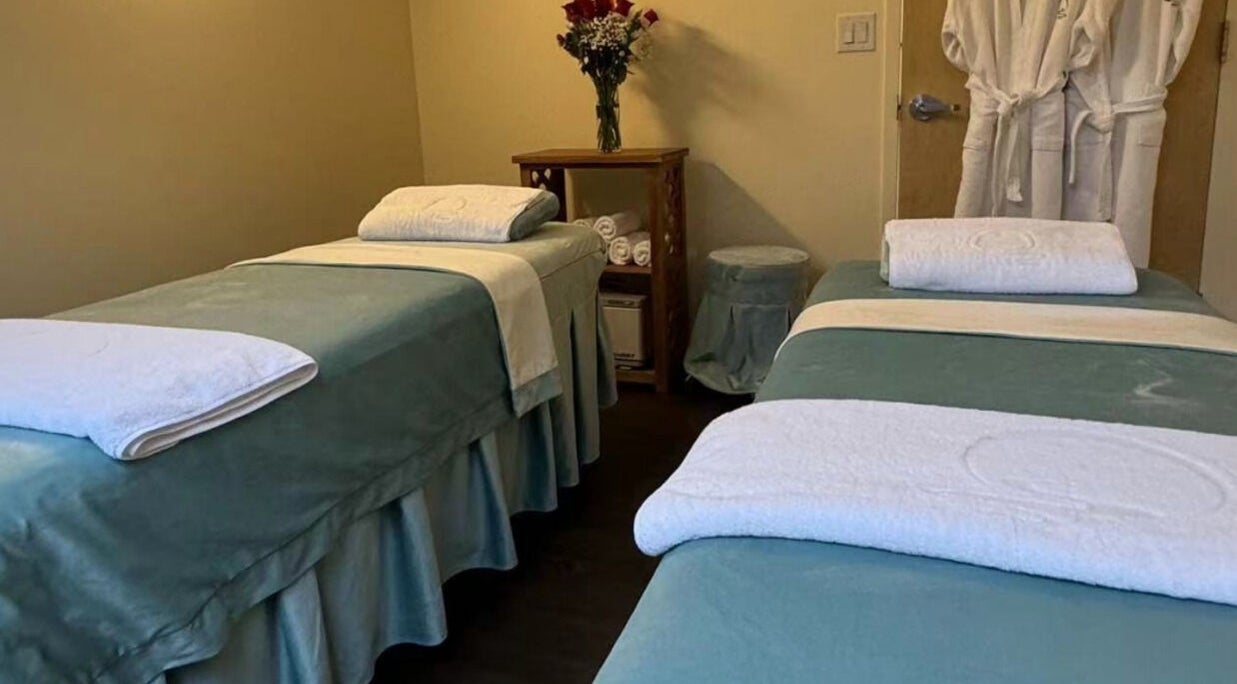 Two massage tables at Relax Day Spa, New York, New York, US, adorned with fresh linens and roses.