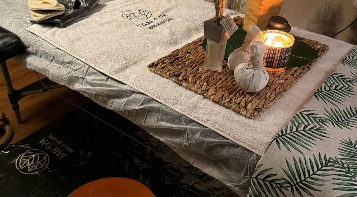 طاولة تدليك مزينة في مركز تان سبا للخدمة المنزلية، الرياض، تتميز بلمسات فاخرة لمزيد من الاسترخاء.