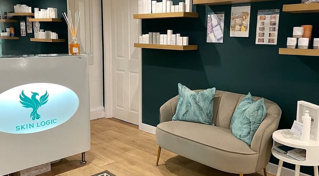 Chic reception at Skin Logic, Romsey, England; cozy couch, stylish shelves displaying beauty products.