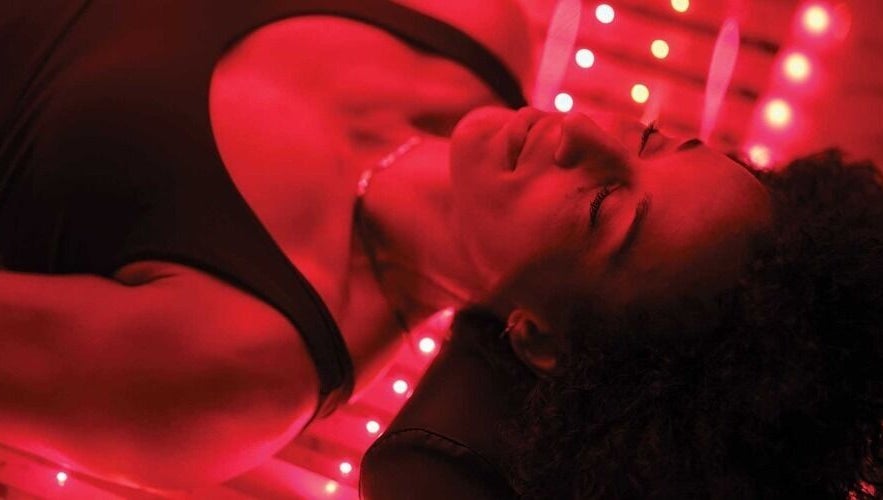Client enjoying infrared therapy at St. M’s Thera Spa, Twickenham, England, GB in a calming red-lit room.