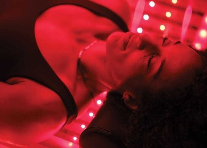 Client enjoying infrared therapy at St. M’s Thera Spa, Twickenham, England, GB in a calming red-lit room.