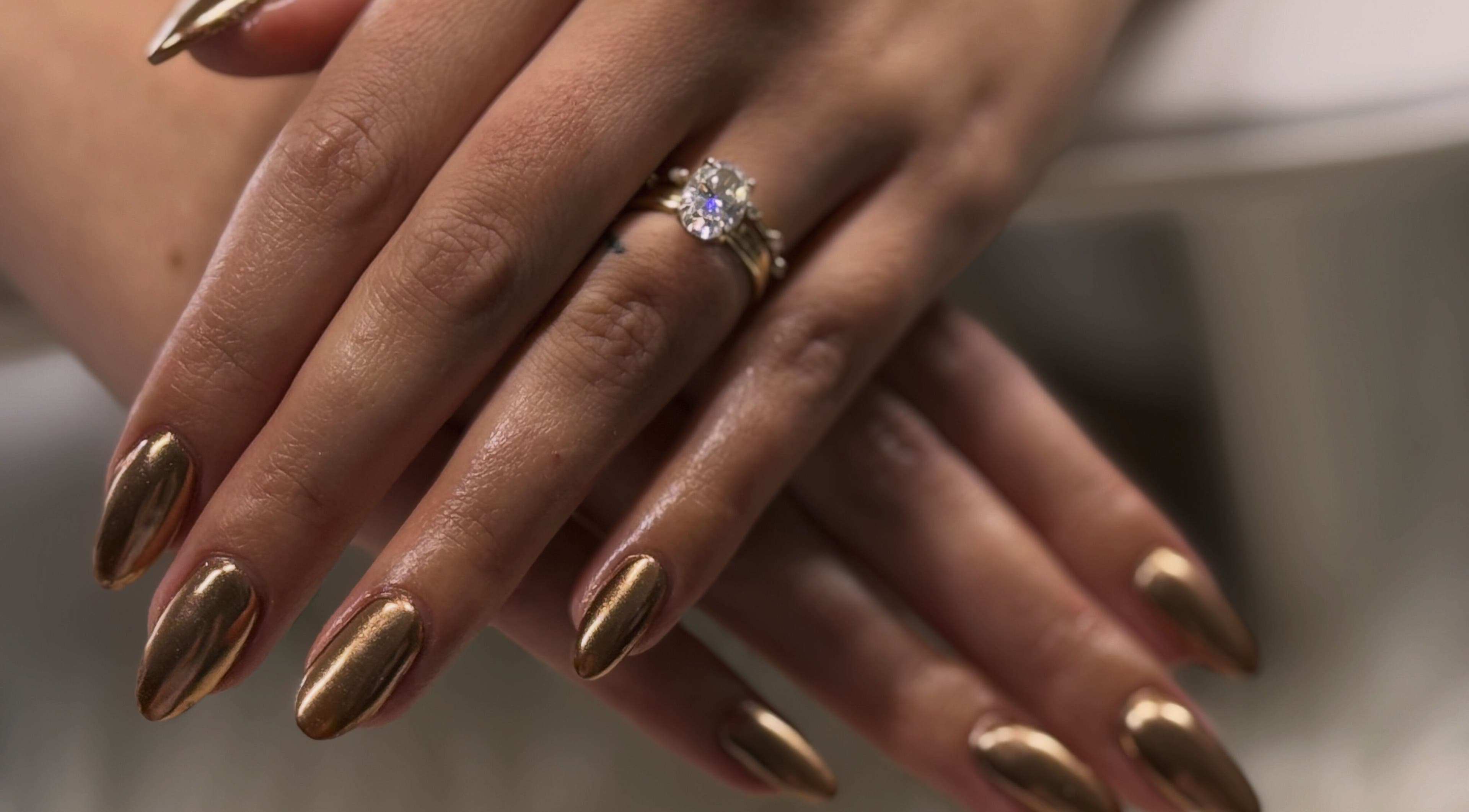 Elegant golden nails with a ring on display at Nailed by Krisana, Liberty Lake, Washington, US.