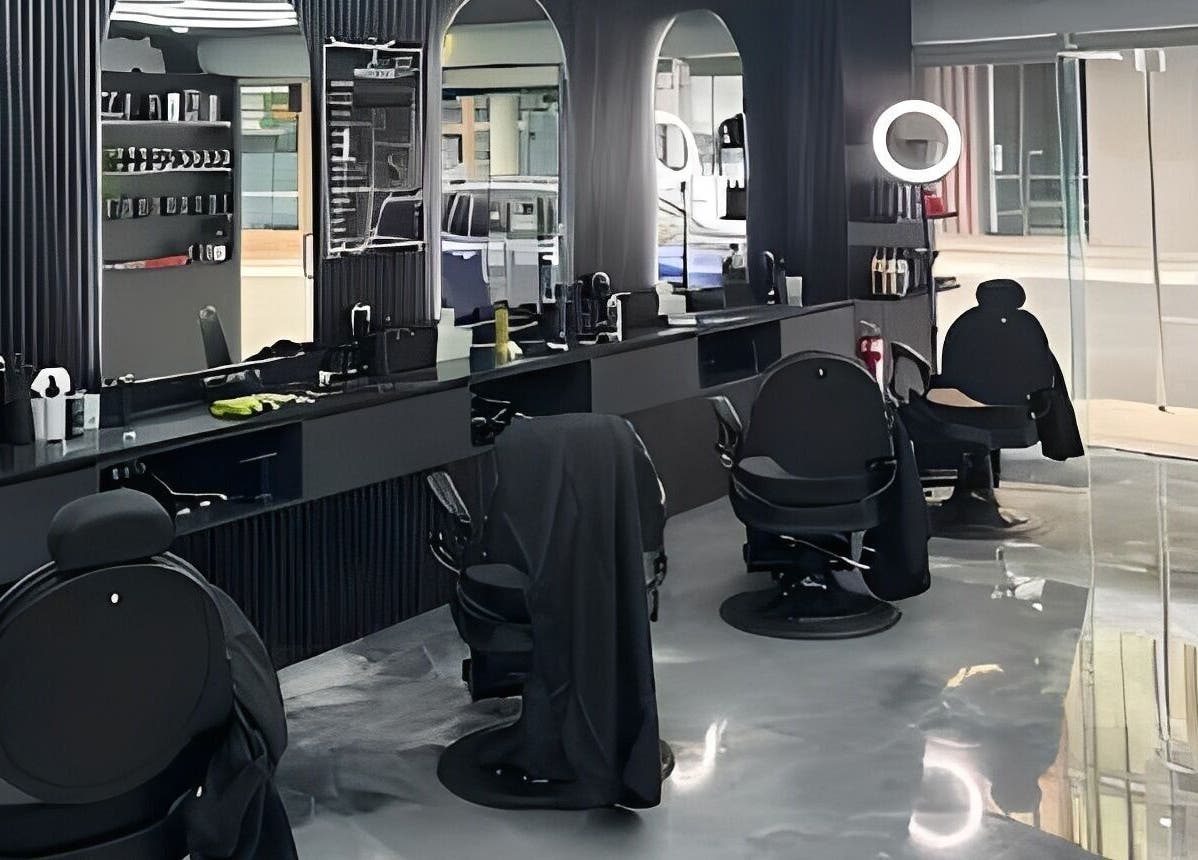Modern interior of JE Barbers in Melbourne, Victoria with sleek black chairs and reflective surfaces.