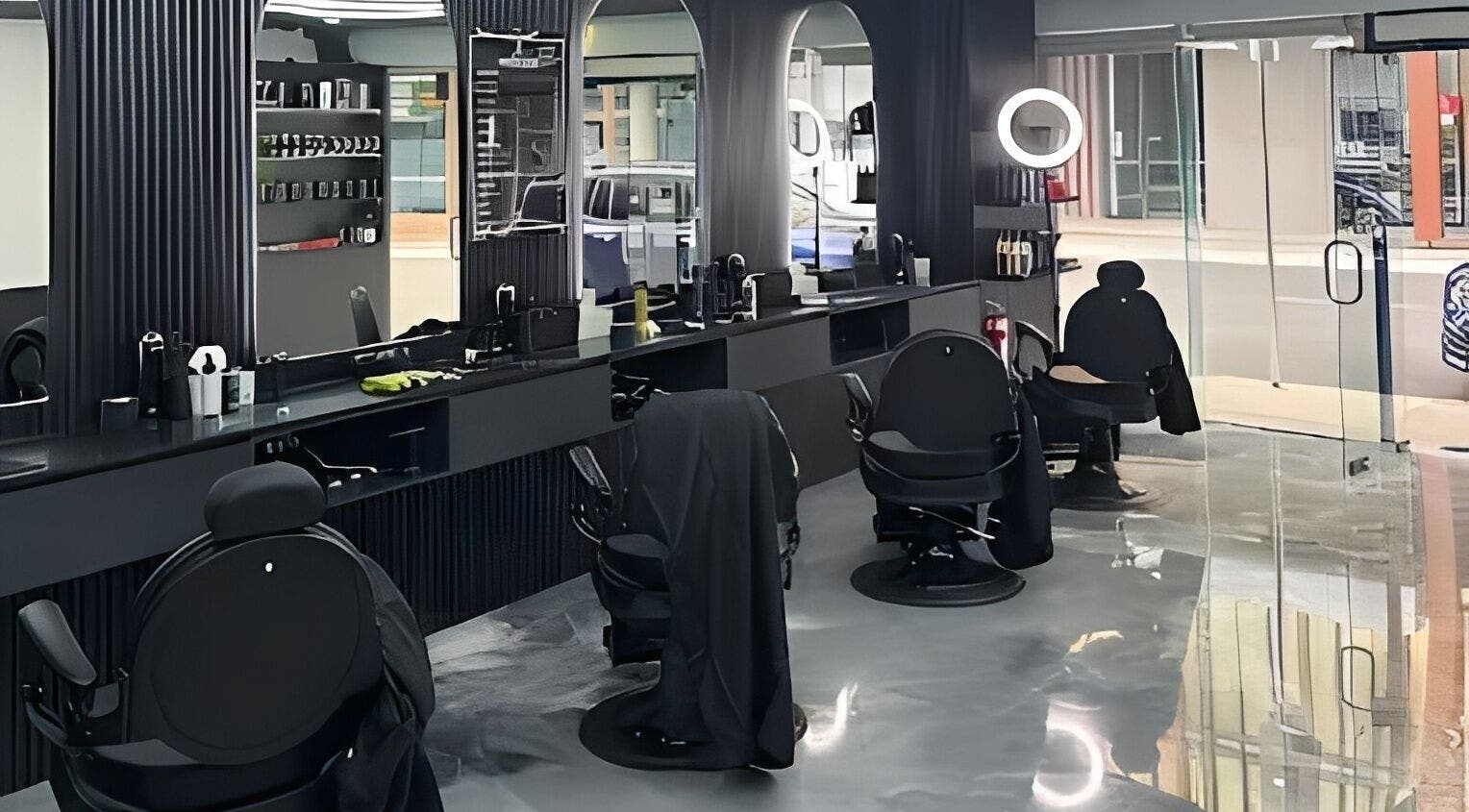 Modern interior of JE Barbers in Melbourne, Victoria with sleek black chairs and reflective surfaces.
